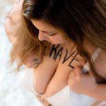 Girl with white bra looking down with the word brave written on her chest